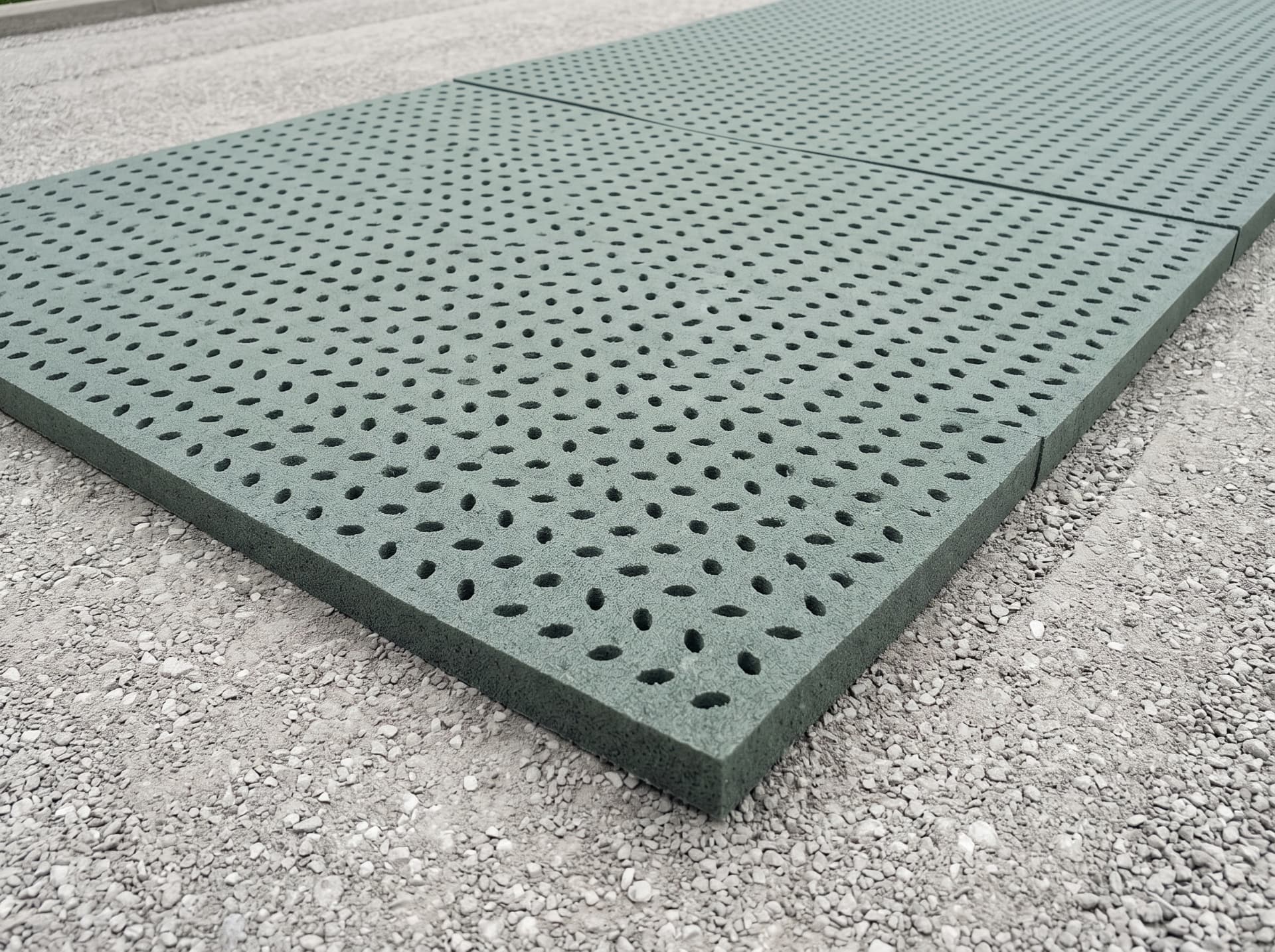 Perforated turf pad panels laid out on a compacted aggregate base