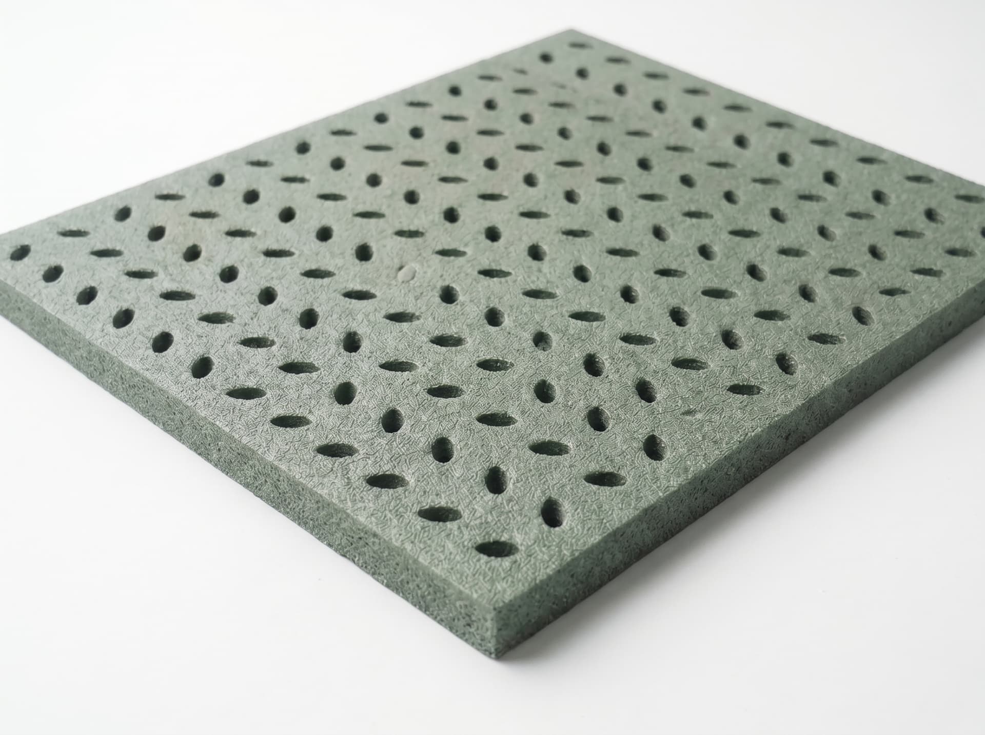Close-up of a green closed-cell turf pad panel with drainage perforations